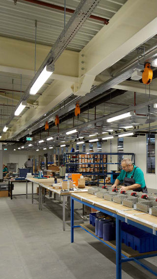An employee works at the Venco Campus production area, lit brightly thanks to Philips industrial lighting