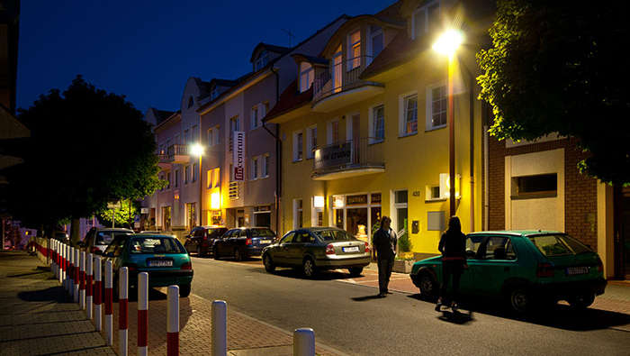 أشخاص يتجولون ليلاً في شارع مضاء باستخدام إضاءات Philips للشوارع 