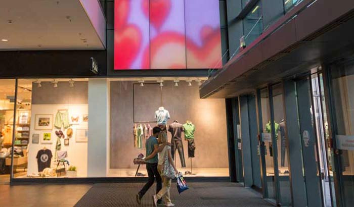 رجل وامرأة يحدّقان في اللوحة النسيجية المضيئة دائمة التغيّر في مول تسوّق Centrum Galerie